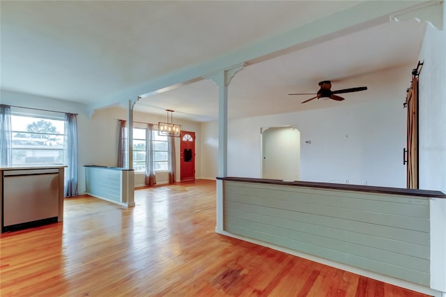 empty room with ceiling fan with notable chandelier and light hardwood / wood-style flooring