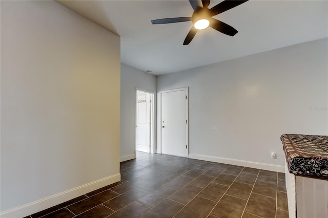 empty room with ceiling fan and dark tile patterned flooring