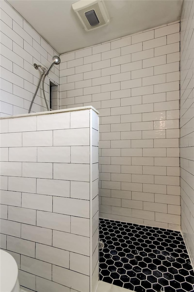 bathroom with toilet and a tile shower