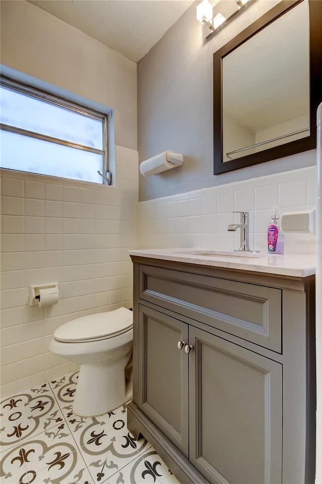 bathroom featuring toilet, vanity, tile walls, and tile patterned floors