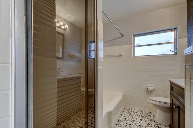 full bathroom featuring tile patterned floors, vanity, shower with separate bathtub, tile walls, and toilet