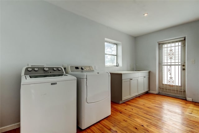 washroom featuring washer and dryer, cabinets, sink, and light wood-type flooring