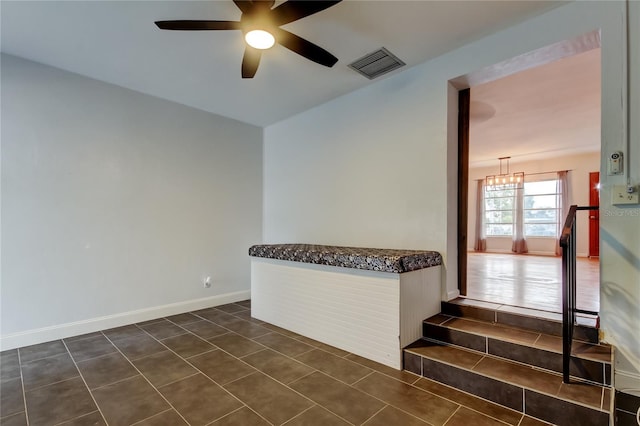 unfurnished room featuring dark tile patterned flooring and ceiling fan with notable chandelier