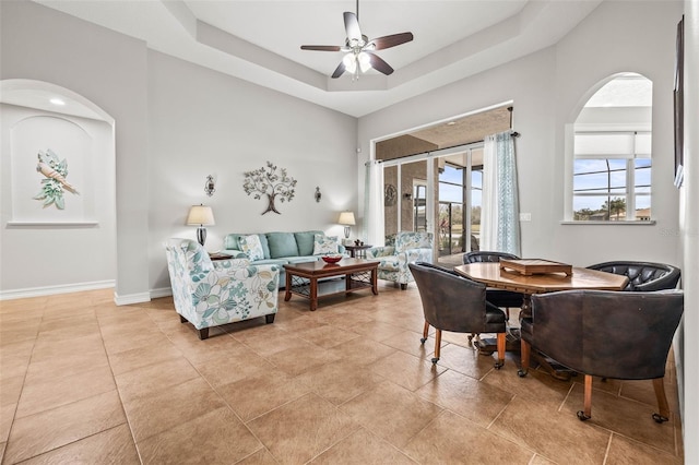 living room featuring ceiling fan and a tray ceiling