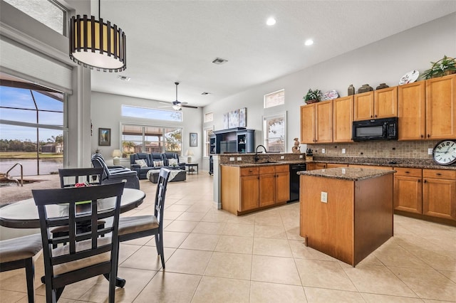 kitchen featuring kitchen peninsula, ceiling fan, dark stone counters, a kitchen island, and black appliances