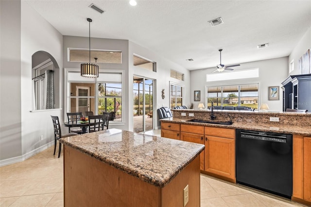 kitchen with decorative light fixtures, sink, dishwasher, and light stone countertops