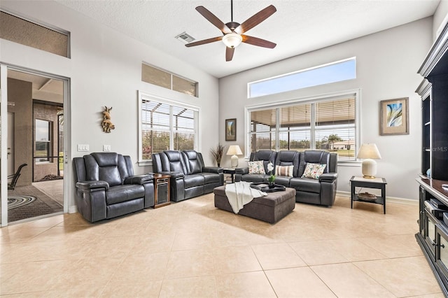 living room with ceiling fan, plenty of natural light, a textured ceiling, and light tile patterned floors