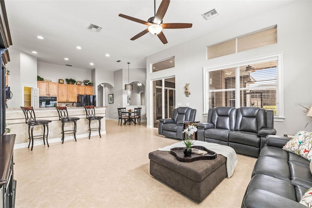 tiled living room featuring ceiling fan and a towering ceiling