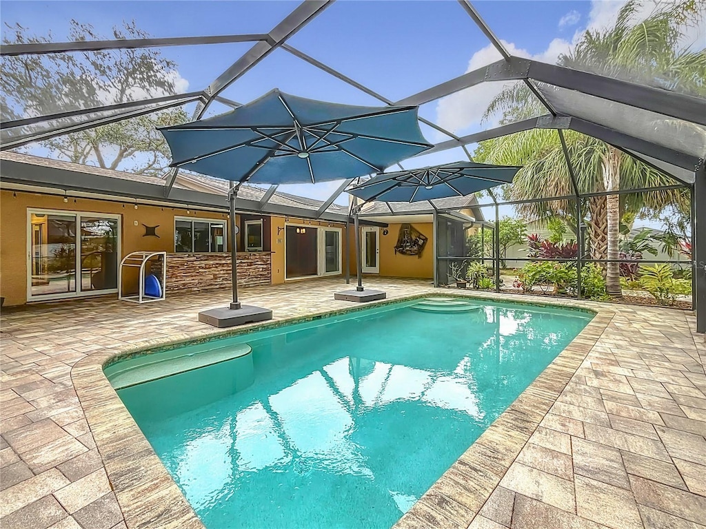 view of pool with glass enclosure and a patio area