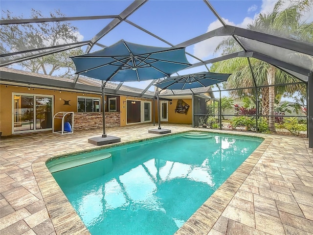 view of pool with glass enclosure and a patio area