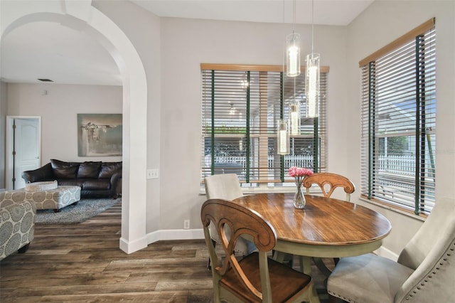 dining area with dark wood-type flooring, a wealth of natural light, and an inviting chandelier