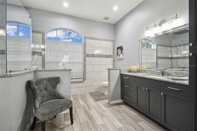 bathroom with tiled shower, vanity, and toilet