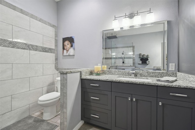 bathroom featuring tile patterned floors, toilet, vanity, and a tile shower