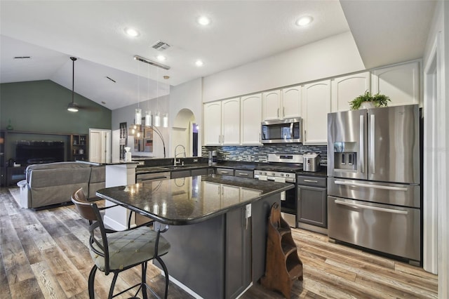 kitchen featuring kitchen peninsula, appliances with stainless steel finishes, tasteful backsplash, pendant lighting, and white cabinets