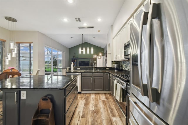 kitchen featuring a center island, stainless steel appliances, sink, hanging light fixtures, and a breakfast bar area