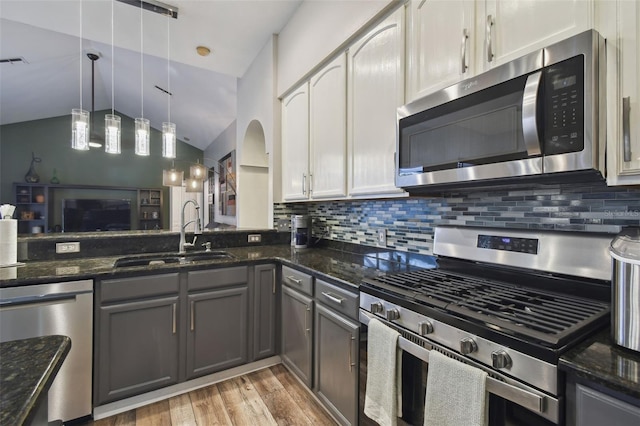 kitchen featuring appliances with stainless steel finishes, white cabinets, dark stone counters, and sink