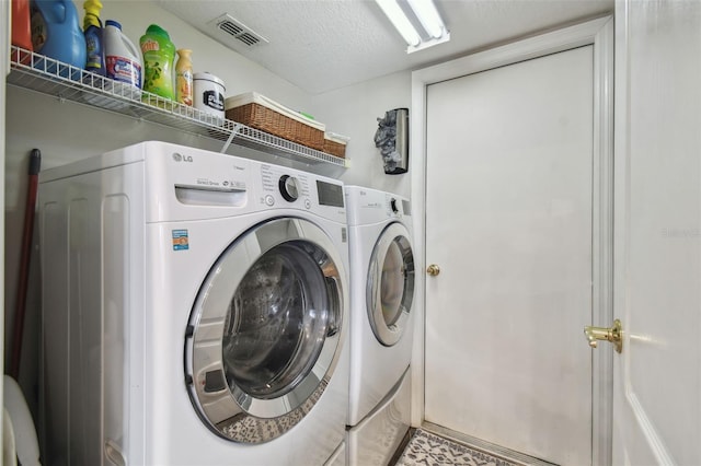 laundry room with a textured ceiling and separate washer and dryer