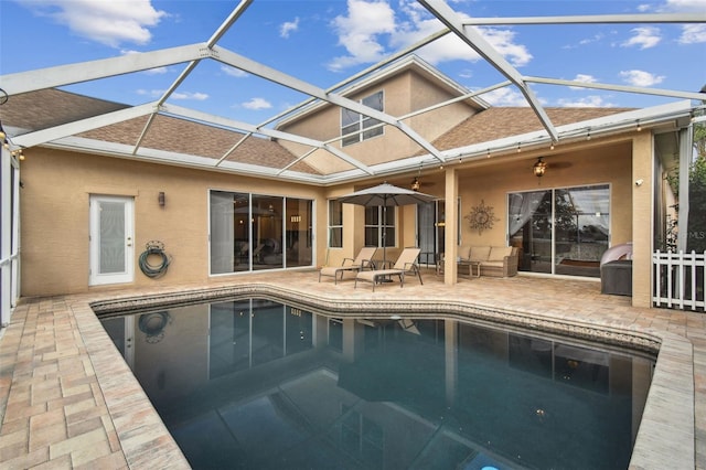 view of swimming pool featuring ceiling fan, a lanai, and a patio area