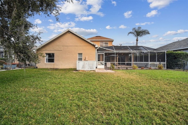 rear view of property with glass enclosure and a yard