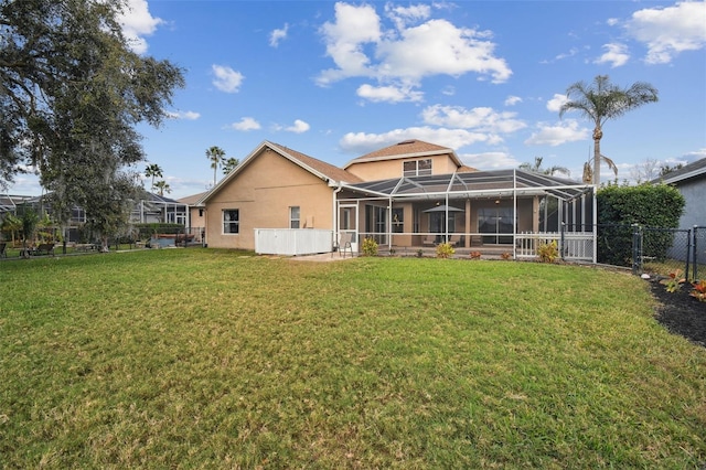 back of house with a lanai and a lawn