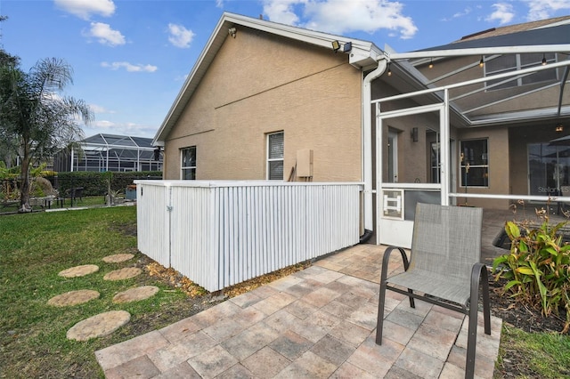 view of side of property with a yard, a patio area, and glass enclosure