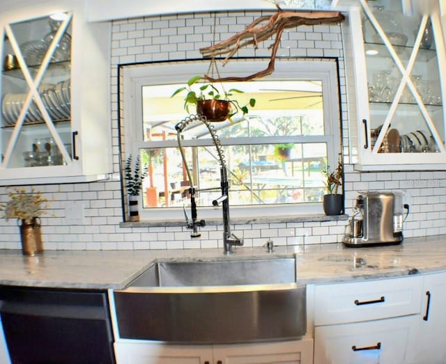 kitchen featuring backsplash, light stone countertops, sink, and white cabinets