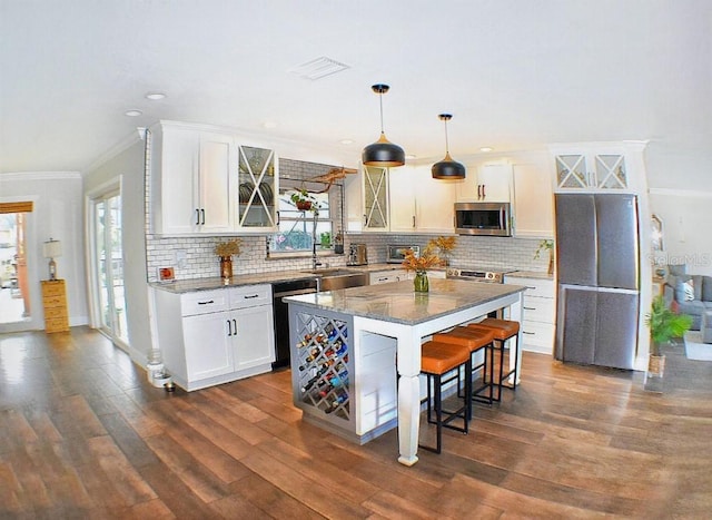 kitchen with stainless steel appliances, decorative light fixtures, a center island, and white cabinets