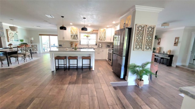 225 Temple Cir, Eustis, FL 32726 - kitchen featuring appliances with stainless steel finishes, crown molding, a center island, glass insert cabinets, and white cabinetry