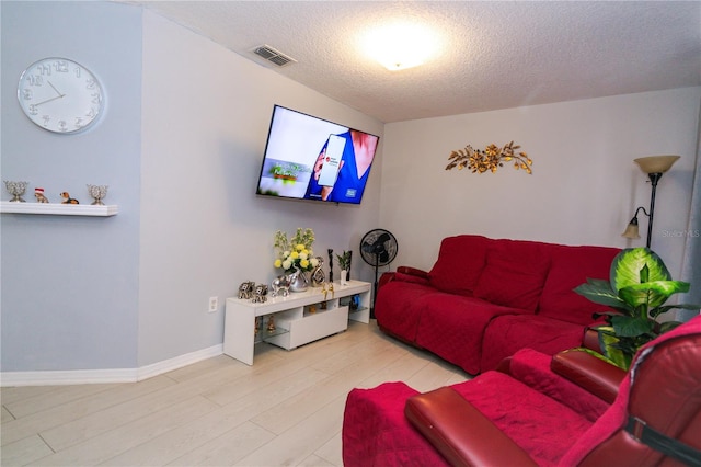 living room with a textured ceiling and light wood-type flooring