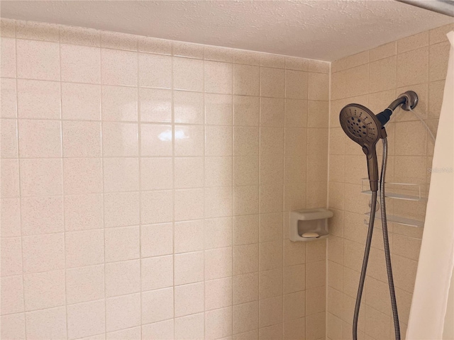 interior details featuring tiled shower and a textured ceiling