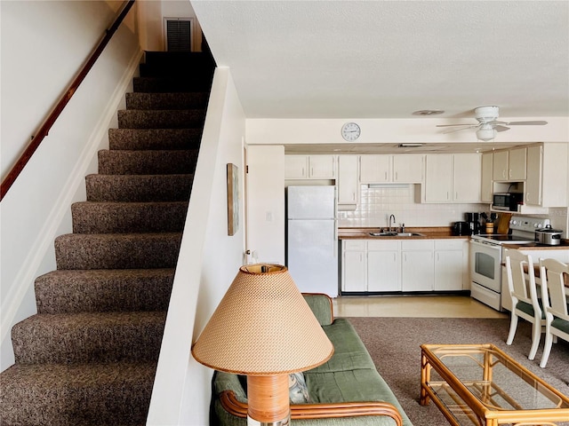 kitchen featuring tasteful backsplash, sink, white cabinets, ceiling fan, and white appliances