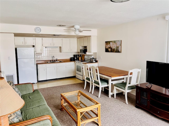 kitchen featuring sink, white cabinetry, light carpet, white appliances, and decorative backsplash