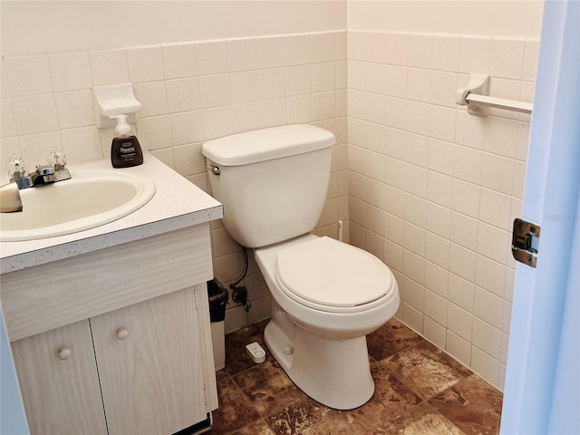 bathroom with vanity, tile walls, and toilet