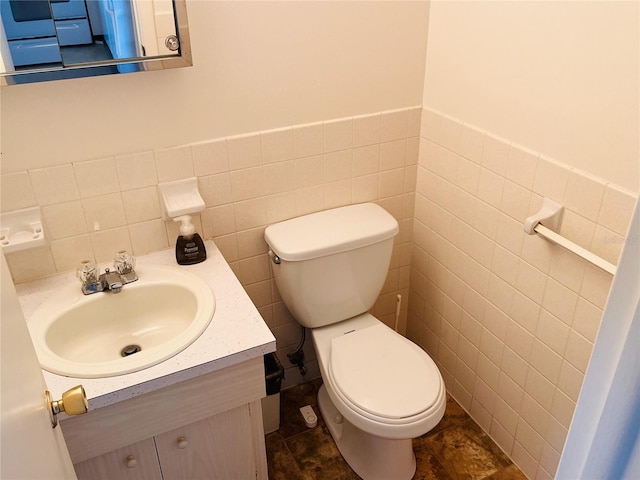 bathroom with vanity, tile walls, and toilet