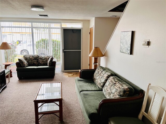 carpeted living area with a textured ceiling and visible vents