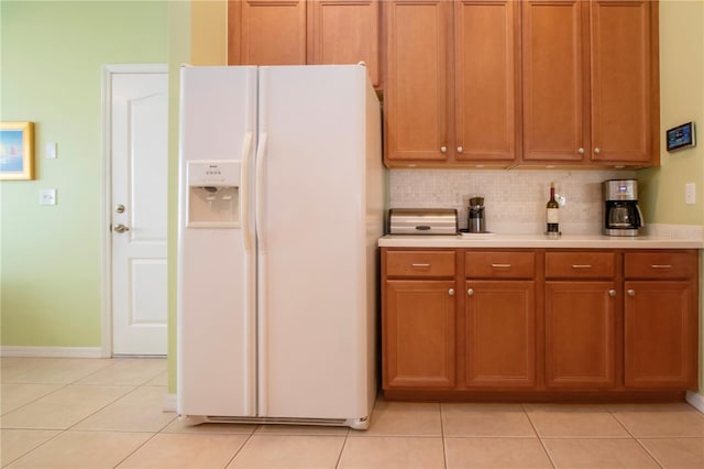 kitchen featuring light tile patterned floors, decorative backsplash, and white refrigerator with ice dispenser