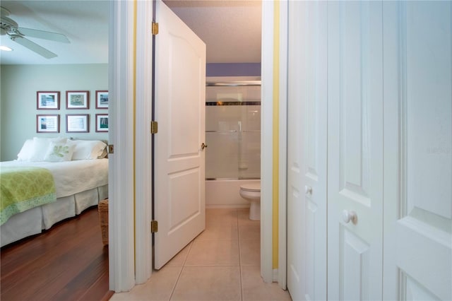 interior space featuring ceiling fan, connected bathroom, light tile patterned floors, and a textured ceiling