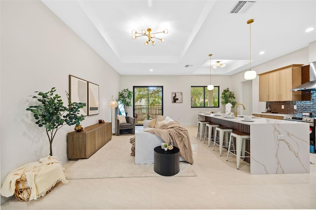 living room with a raised ceiling and a chandelier