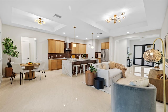 living room featuring sink, a raised ceiling, and an inviting chandelier