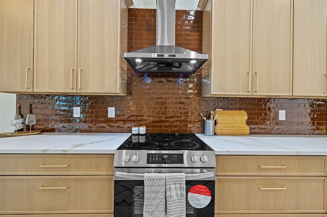 kitchen with decorative backsplash, electric range, light brown cabinetry, wall chimney range hood, and light stone counters