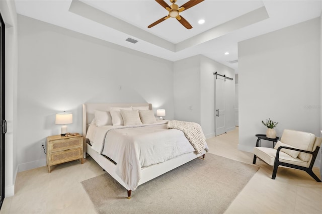 bedroom with a raised ceiling, a barn door, and ceiling fan