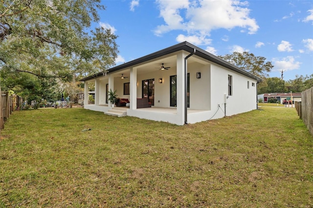 rear view of house featuring ceiling fan, a patio area, and a yard