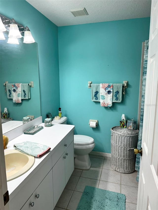 bathroom featuring tile patterned flooring, vanity, a textured ceiling, and toilet