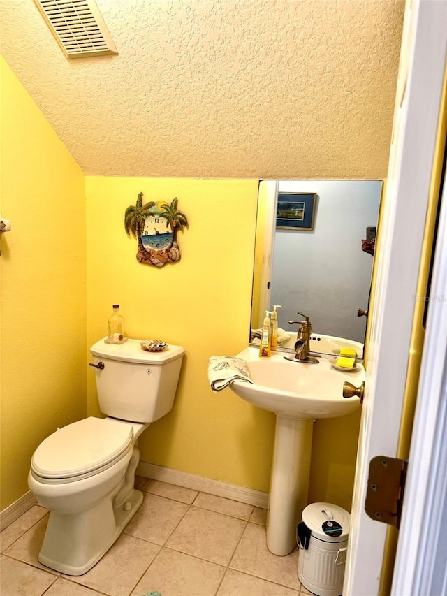 bathroom featuring tile patterned flooring, lofted ceiling, and toilet