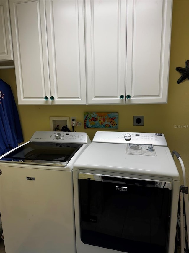 clothes washing area with cabinets and washer and dryer