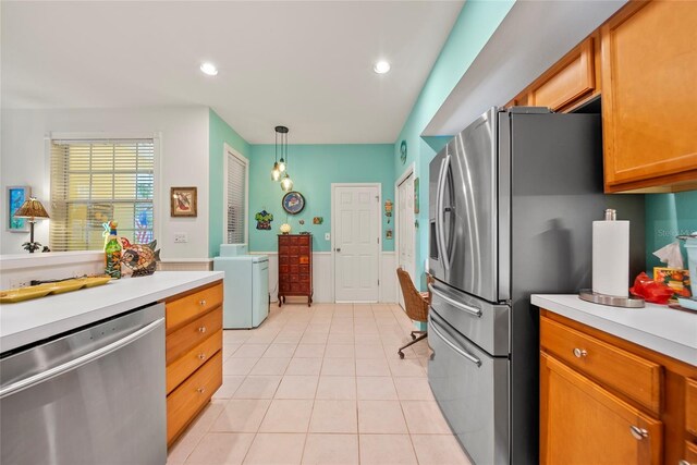 458 Grant St, Dunedin, FL 34698 - kitchen with appliances with stainless steel finishes, washer / dryer, light countertops, light tile patterned floors, and decorative light fixtures