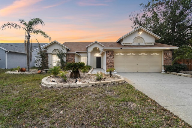 ranch-style house with a garage and a lawn