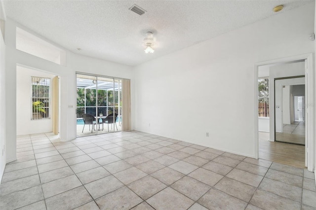 spare room with light tile patterned flooring and a textured ceiling