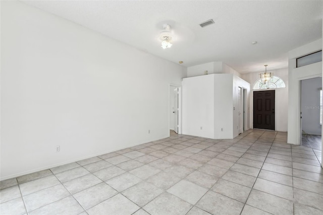 tiled empty room with a notable chandelier