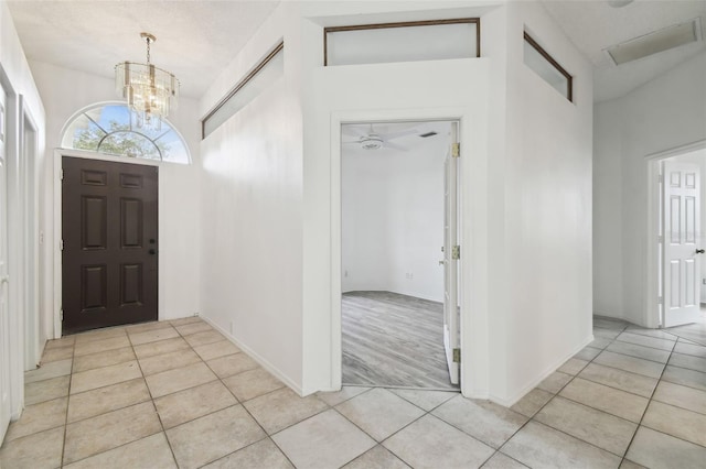 foyer with ceiling fan with notable chandelier and light tile patterned flooring